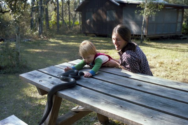 Judy Kern and filmmaker Richard Kern as a toddler inspect a large indigo snake